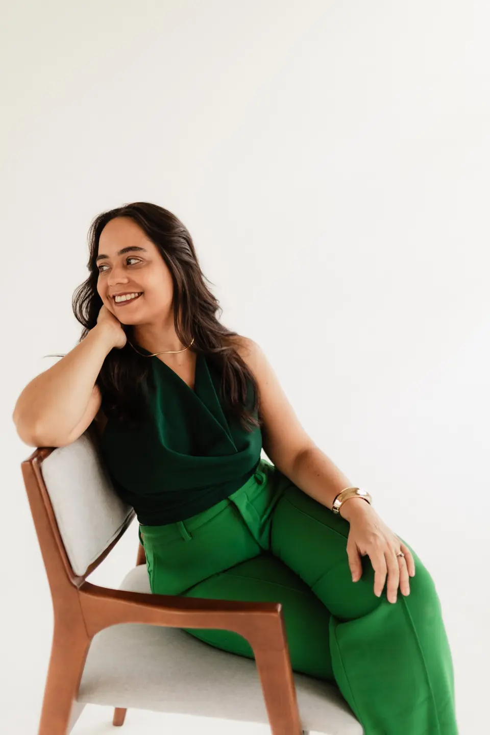 Ignes Valessa, advogada, sentada em uma poltrona de madeira, sorrindo